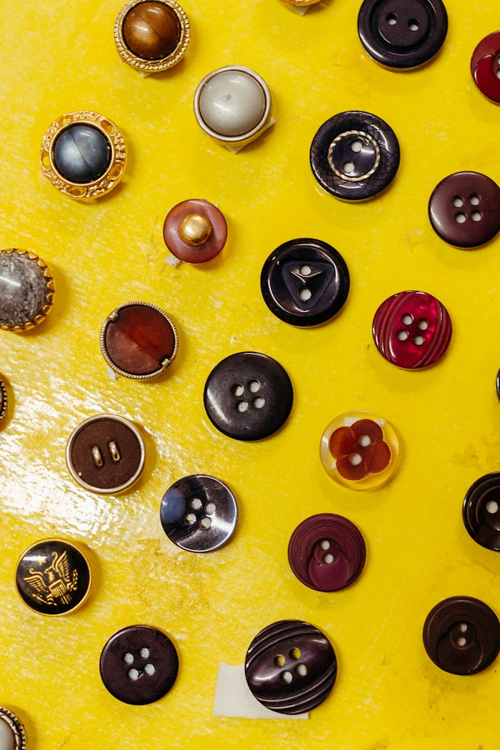 Variety of buttons displayed on a yellow background, showcasing colorful designs and textures.