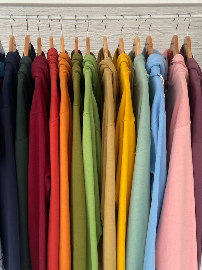 A row of bright hoodies neatly hung in a closet, showcasing a rainbow of colors.