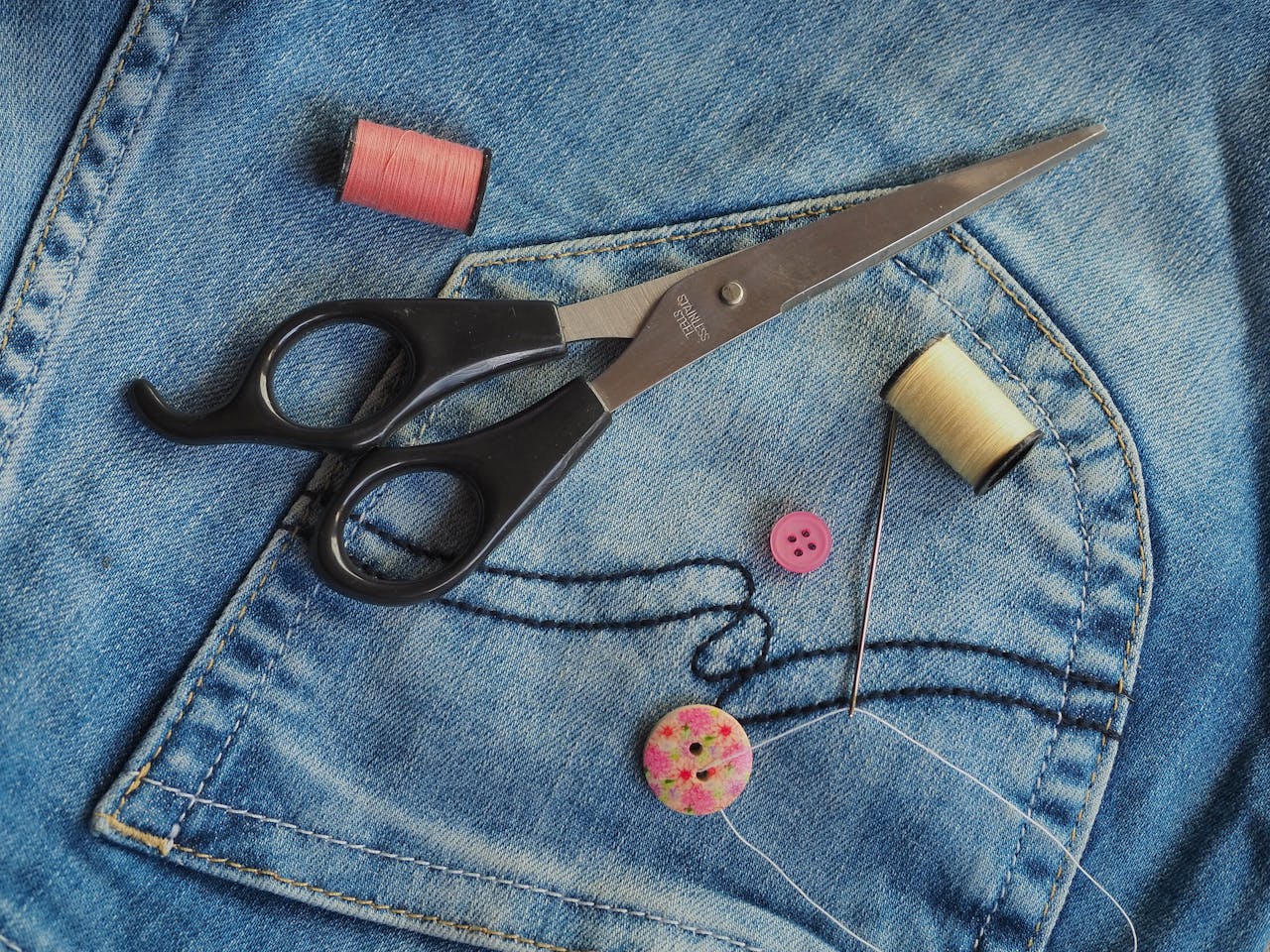 Colorful sewing supplies arranged on blue denim fabric. Ideal for crafting themes.