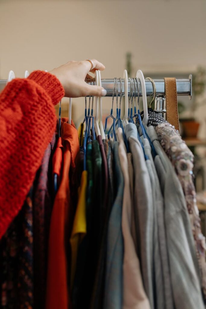 pexels photo 6068960 A woman browsing garments on hangers in a retail clothing store.